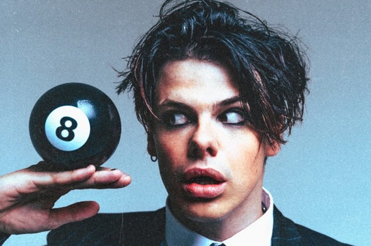 Photo of Yungblud in a suit holding a giant 8 ball